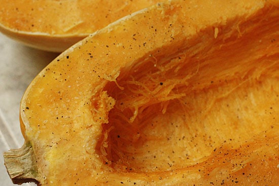 Learn how to cook spaghetti squash using this foolproof baked spaghetti squash recipe. It's quick, easy, and comes out tender every time! Spaghetti squash cut in half with the seeds removed, seasoned and ready for the oven.