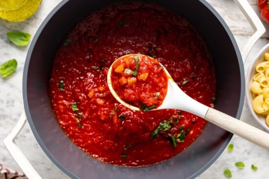 This filetto di pomodoro tastes far better than store-bought pasta sauces! You only need a few ingredients for this authentic Italian recipe. Spoonful of chunky filetto di pomodoro sauce held over pot.