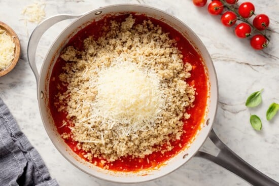Cheese and quinoa added to skillet of tomato sauce.