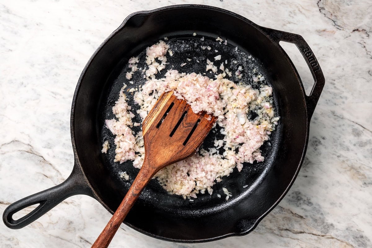 Diced shallots sautéing in a skillet.