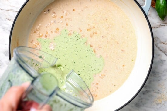 Pouring basil cream sauce into pan.