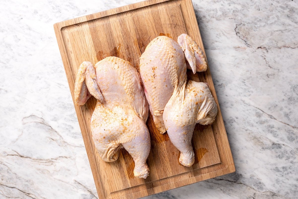 This juicy, restaurant-style Peruvian chicken is marinated overnight and oven-roasted for golden, crispy skin. Served with spicy green sauce. A whole Peruvian marinated chicken, cut in half on a cutting board.