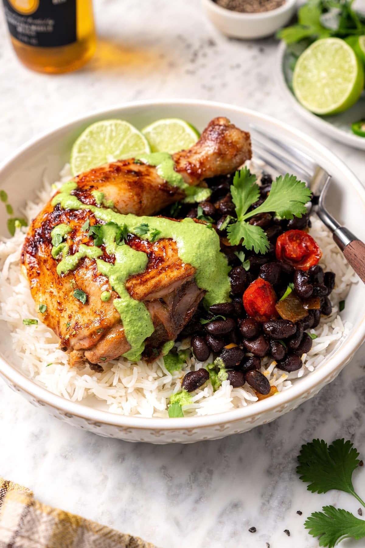 This juicy, restaurant-style Peruvian chicken is marinated overnight and oven-roasted for golden, crispy skin. Served with spicy green sauce. Peruvian roasted chicken served over rice and beans, drizzled with spicy green sauce.