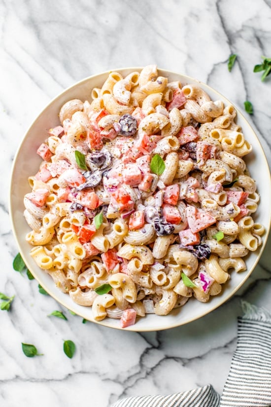 A lighter version of macaroni salad with tomatoes and black olives is the perfect side dish for summer barbecues.