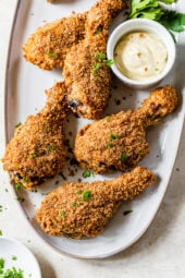 Oven fried chicken on platter with bowl of dipping sauce.
