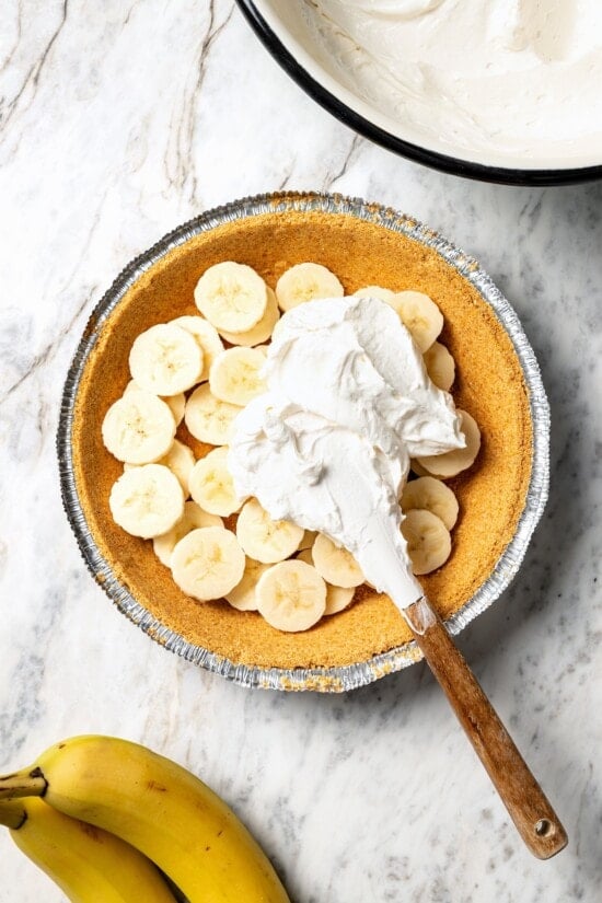 Adding banana cream pie filling to crust.