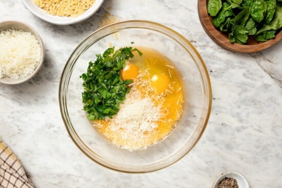Eggs, Parmesan, and parsley in glass bowl.