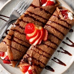 Two chocolate crepes filled with strawberries and whipped cream.