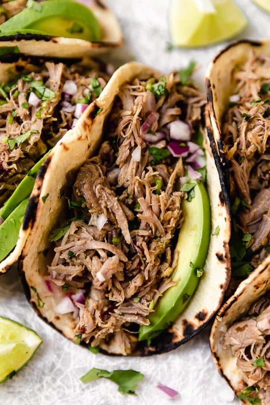 Slow cooked until tender then crisped in the oven, these pork carnitas are practically effortless to make and perfect for meal prep. Closeup of pork carnitas taco with avocado.
