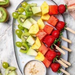 Rainbow fruit kabobs on platter with dip