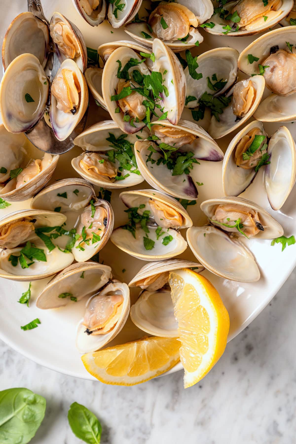 Platter of steamed clams with lemon wedges.