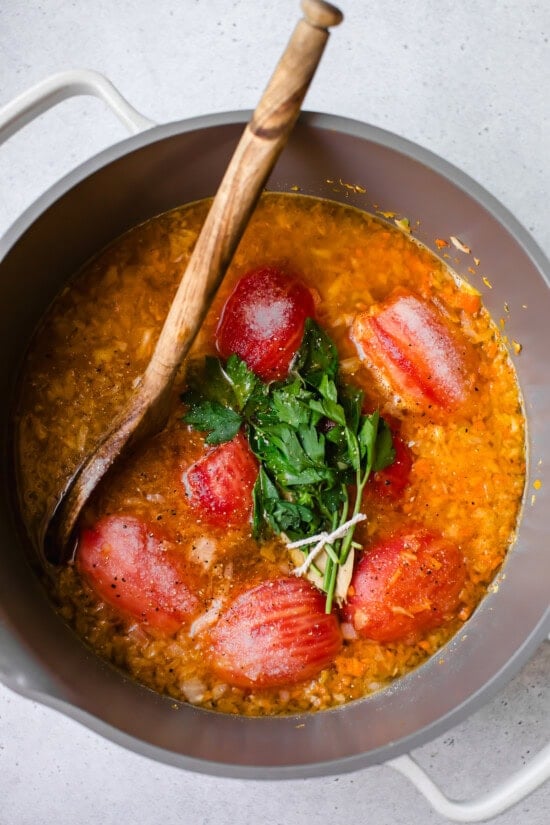 peeled tomatoes and herbs in pot