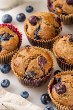 Whole wheat blueberry muffins on counter with fresh blueberries