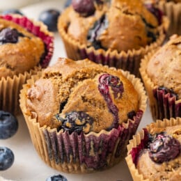 Blueberry muffins on countertop with fresh blueberries