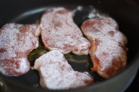 Raw seasoned pork chops placed in pan.