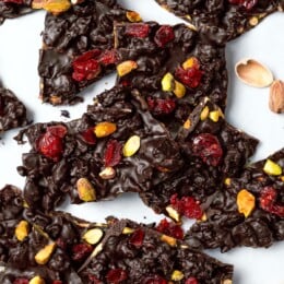 Pile of dark chocolate bark with pistachios and cranberries.
