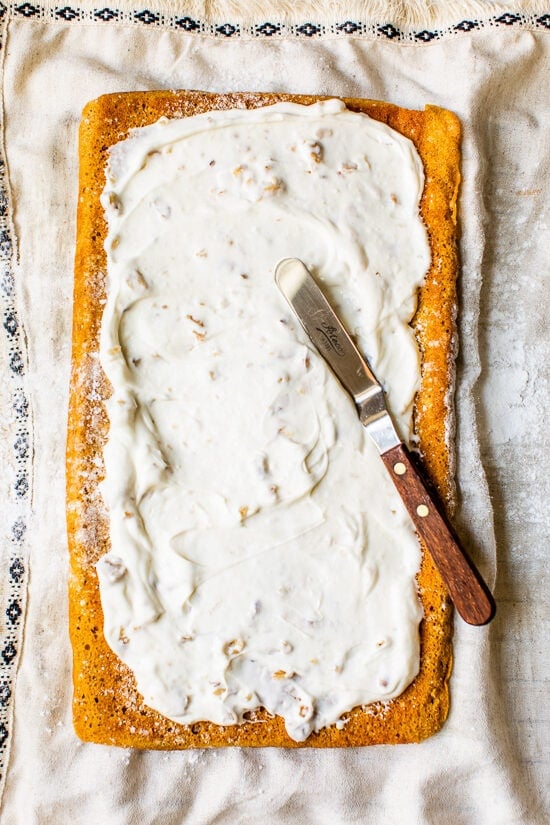 Cream cheese filling spread on a pumpkin roll cake