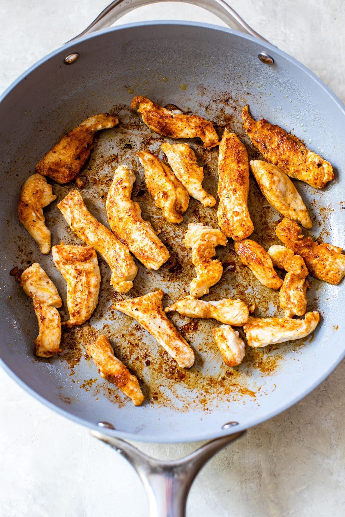 Cajun chicken strips cooked in a skillet.