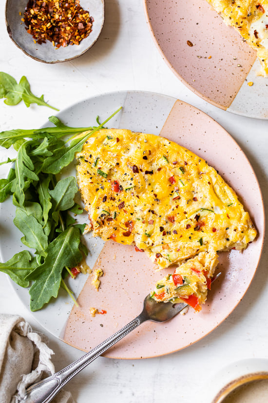 Caramelized onions and sautéed red bell peppers and zucchini mixed with eggs and Parmesan create a winning egg frittata breakfast dish.