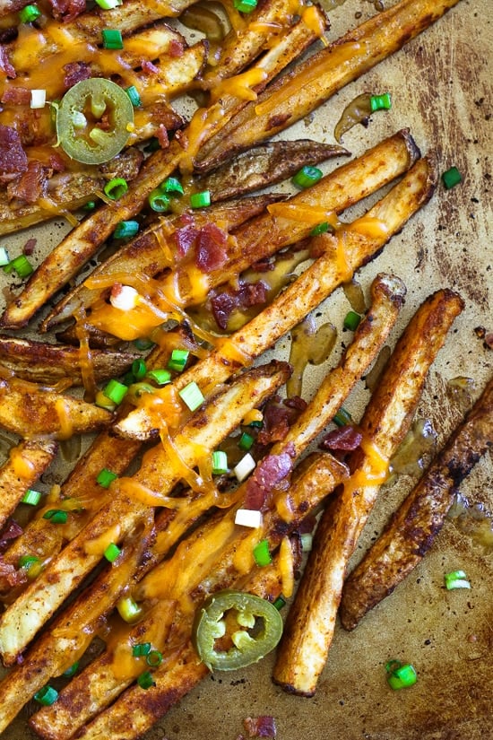 Guiltless cheesy baked seasoned fries topped with bacon, jalapeños and scallions... this is SOOO good! Pure comfort food when cheese fries are what you're craving.