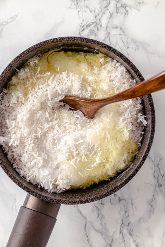 A wooden spoon stirring shredded coconut and egg whites
