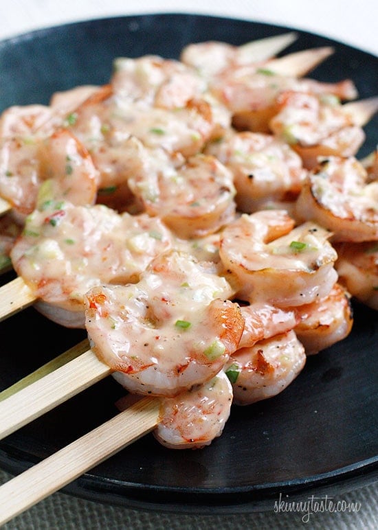 Plate of skewers with grilled shrimp covered with creamy chili sauce