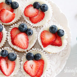 Mini cheesecake cupcakes made with Greek yogurt and cream cheese with a vanilla wafer crust topped with strawberries and blueberries to create a red, white and blue dessert using Mother Nature as my source for food coloring.