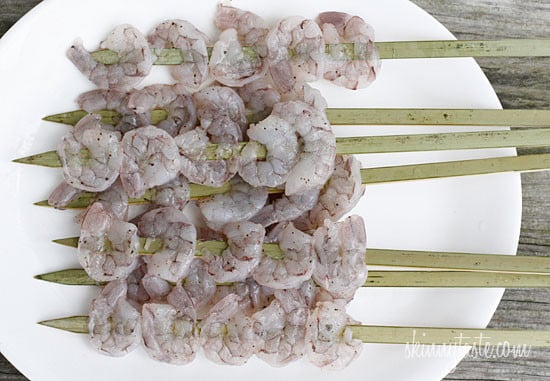 A plate of raw shrimp on skewers