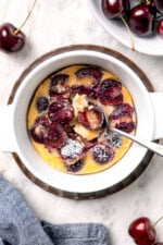 Cherry clafoutis in bowl with spoon.