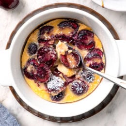 Cherry clafoutis in bowl with spoon.