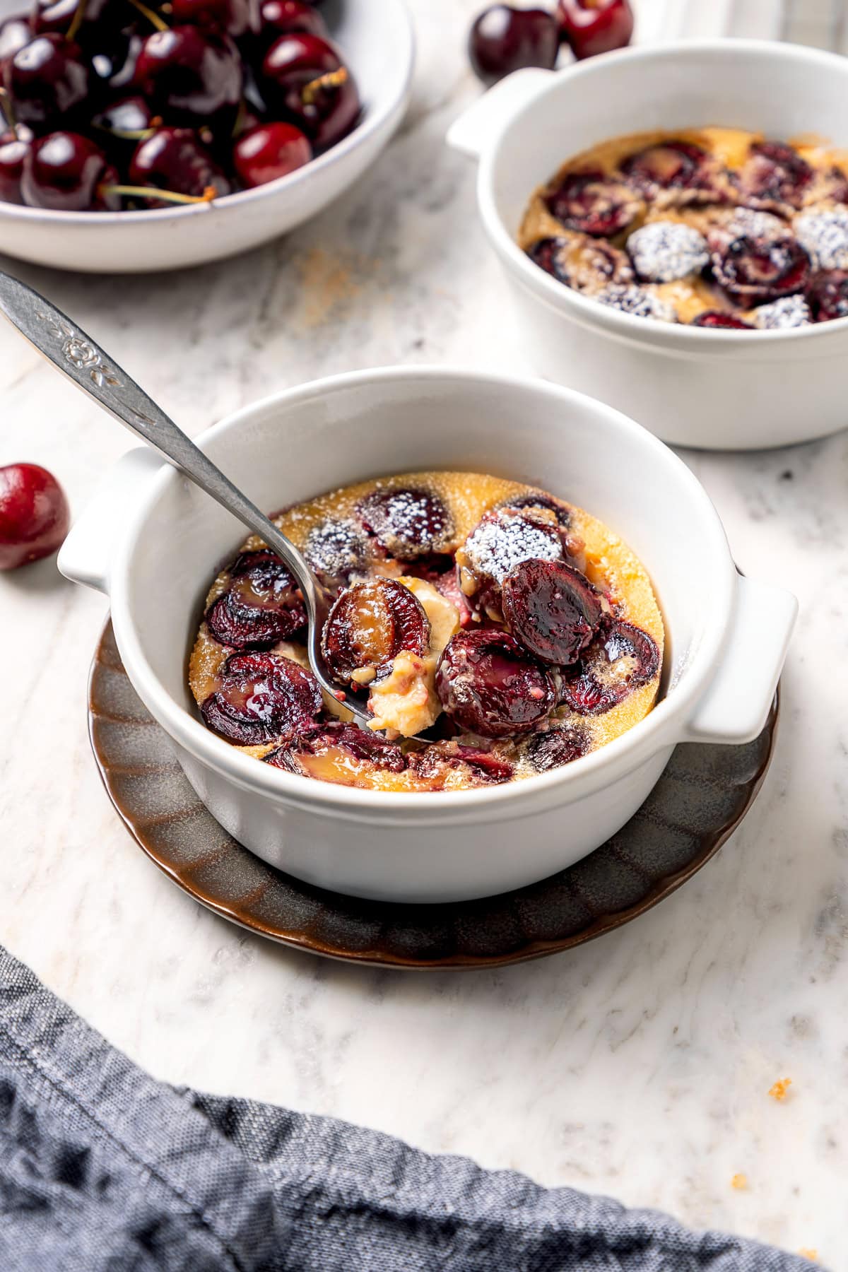 Spoon digging into cherry clafoutis.