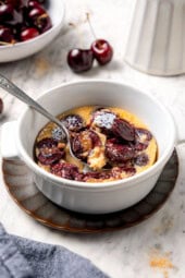 Spoon digging into cherry clafoutis.