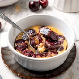 Spoon digging into cherry clafoutis.