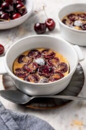Cherry clafoutis in ramekin with powdered sugar dusted on top.