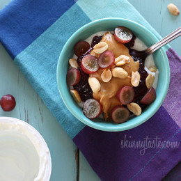 Peanut butter, grape jam, peanuts, and fresh red grapes on top of a bowl of yogurt... who needs the bread!