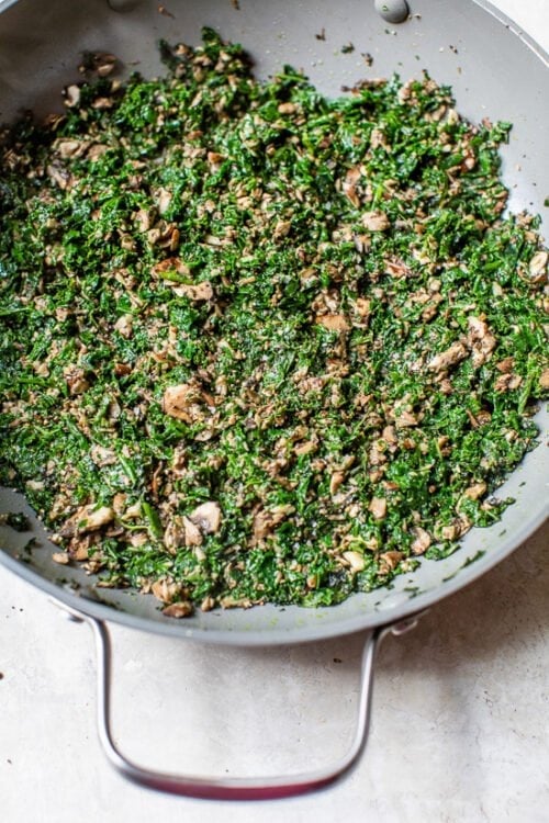 kale in a skillet with mushrooms