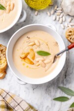 Overhead view of a spoon resting in a bowl of white bean soup.