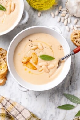 Overhead view of a spoon resting in a bowl of white bean soup.