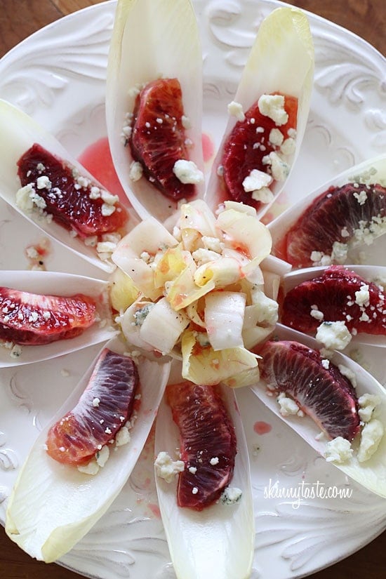 A plate of endive pieces with a blood orange segment in each, topped with crumbled Gorgonzola cheese and blood orange vinaigrette