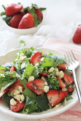 Strawberry salad made with mixed greens, kale and spinach, sliced almonds, crumbled gorgonzola cheese and topped with poppy seed dressing – perfect for summer!