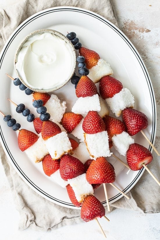 Skewers of red, white and blue fruits with milk cheesecake sauce