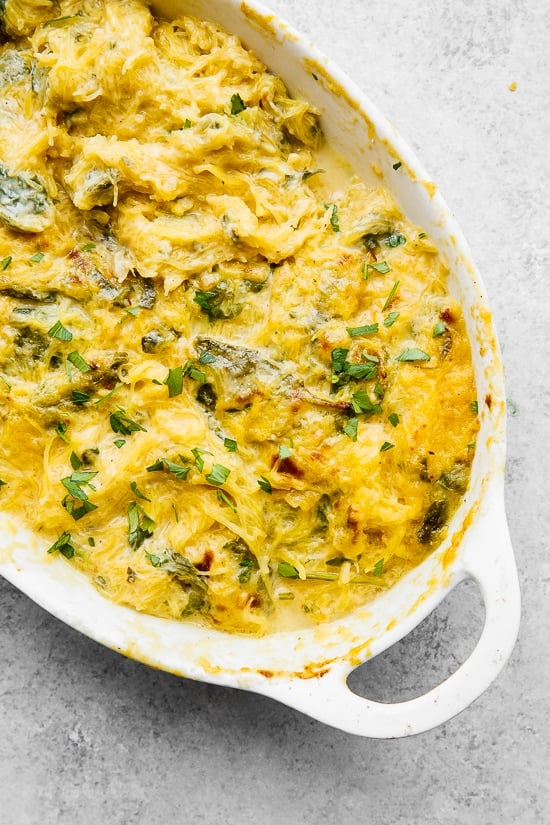 Casserole dish of cheesy baked spaghetti squash with green vegetables