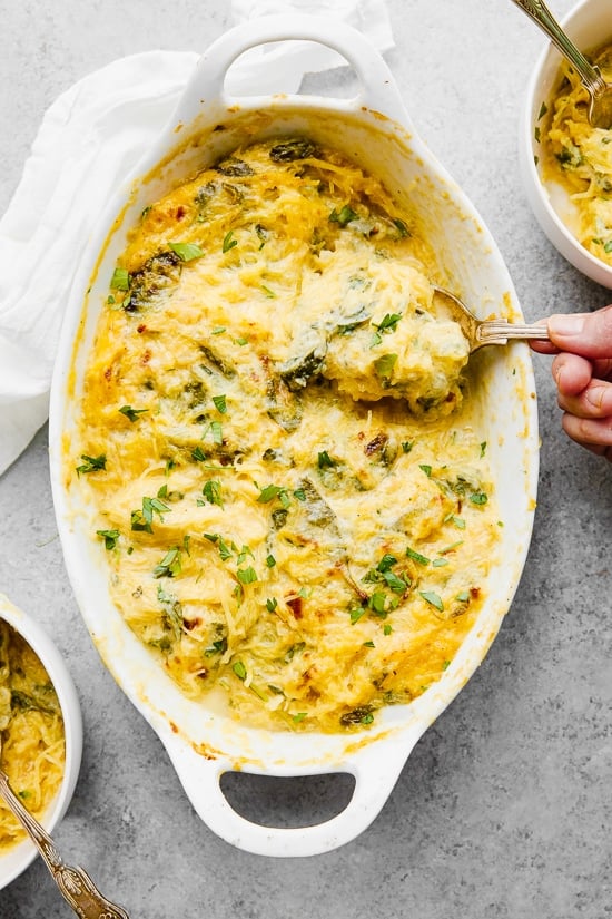 Casserole dish of cheesy baked spaghetti squash with green vegetables
