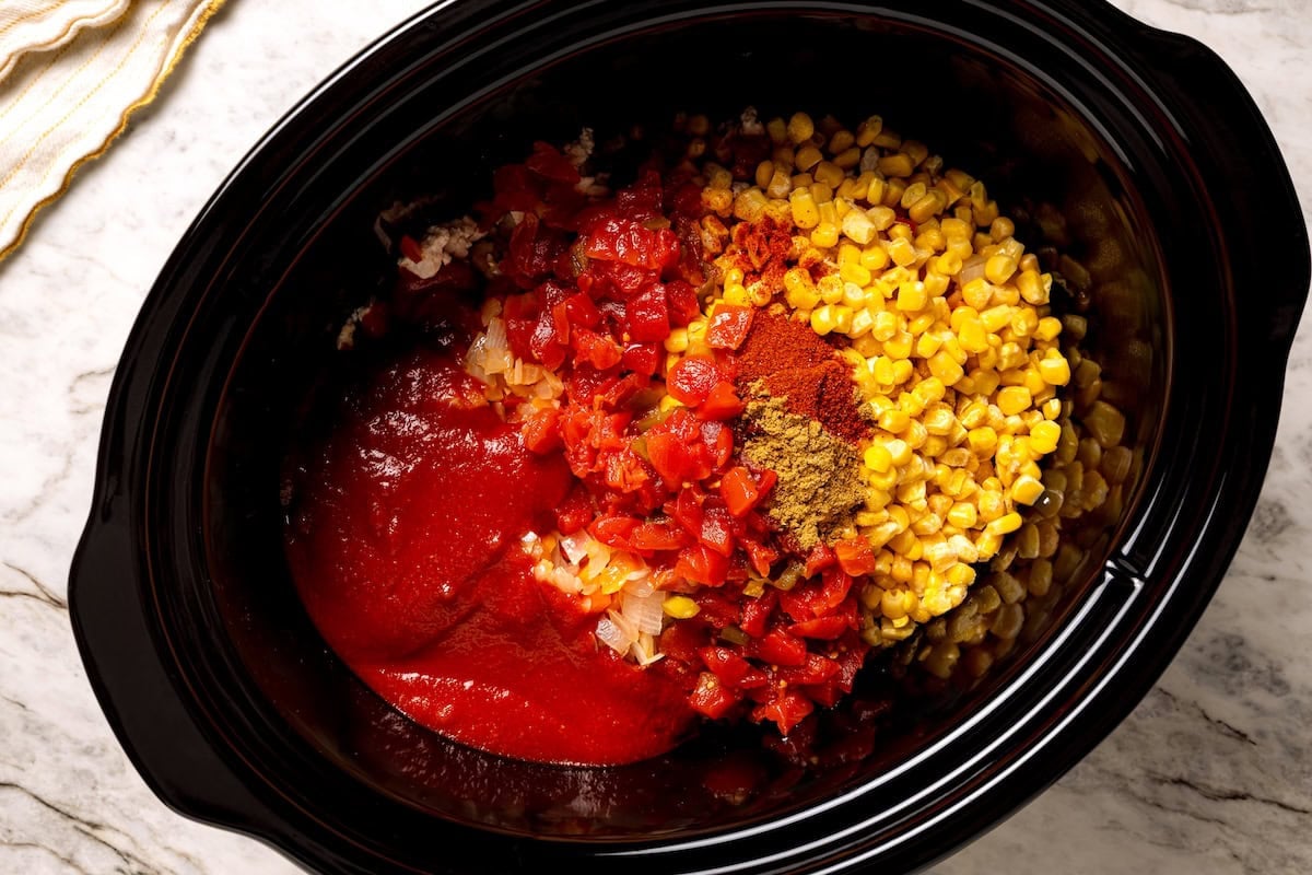 This crock pot turkey chili recipe is easy to make and family-friendly, with ground turkey, corn, bell pepper, tomatoes, and mild spices. Turkey chili ingredients combined in the crock pot.