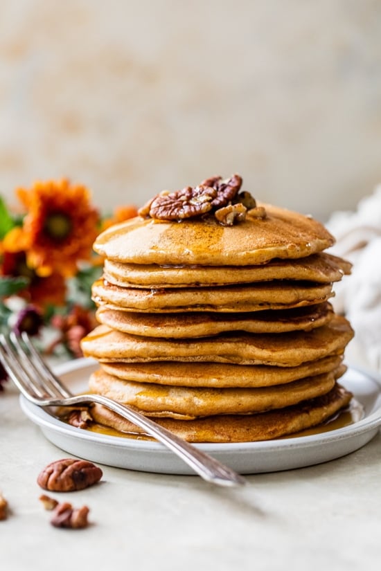 A stack of Whole Wheat Pumpkin Pecan Pancakes with syrup