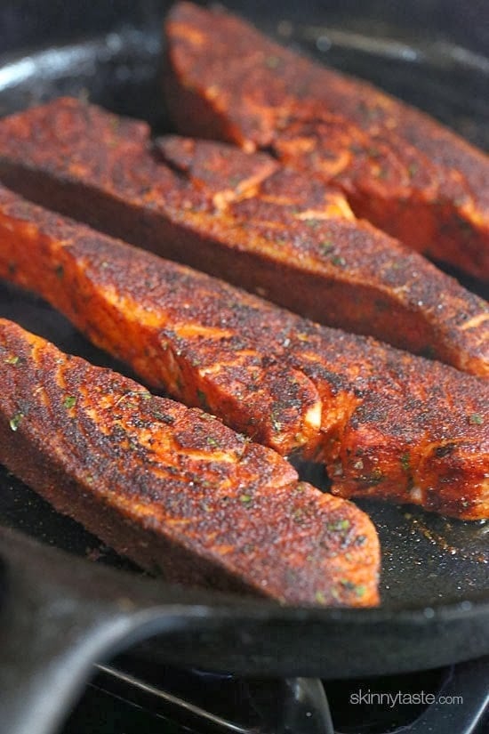Blackened salmon fillets cooking in a cast-iron skillet