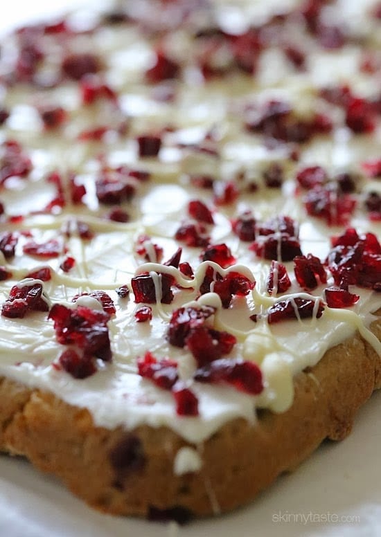 These Makeover Cranberry Bliss Bars are SO good, with more than half the calories and fat of the ones you buy at Starbucks and so much cheaper to make yourself! A blondie cookie bar with chunks of white chocolate chips and dried cranberries, topped with sweet cream cheese icing, tart dried cranberries and white chocolate drizzle – perfect for the holidays!