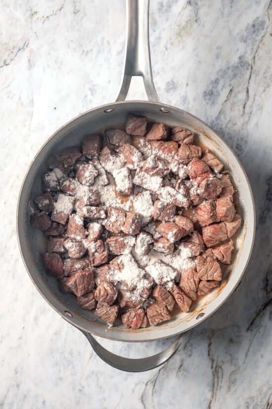 This carne guisada recipe is hearty, flavorful and easy to make in the slow cooker. Tender beef, potatoes and rich sauce make it satisfying! Flour added to skillet of beef.