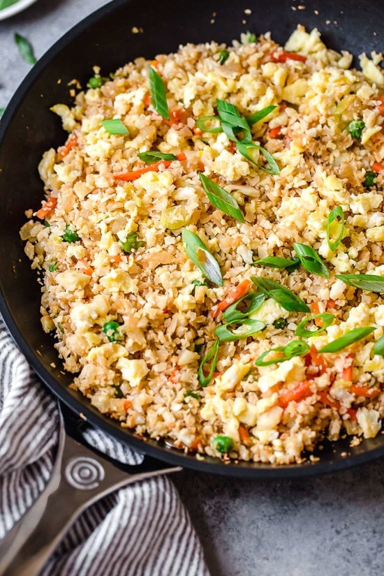 This low-carb cauliflower fried rice recipe is quick, flavorful and a great way to enjoy your favorite takeout-style dish in a lighter way! Cauliflower fried rice in skillet with vegetables and eggs.