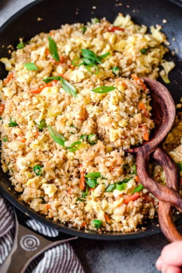 Skillet of cauliflower fried rice with wooden spoon.